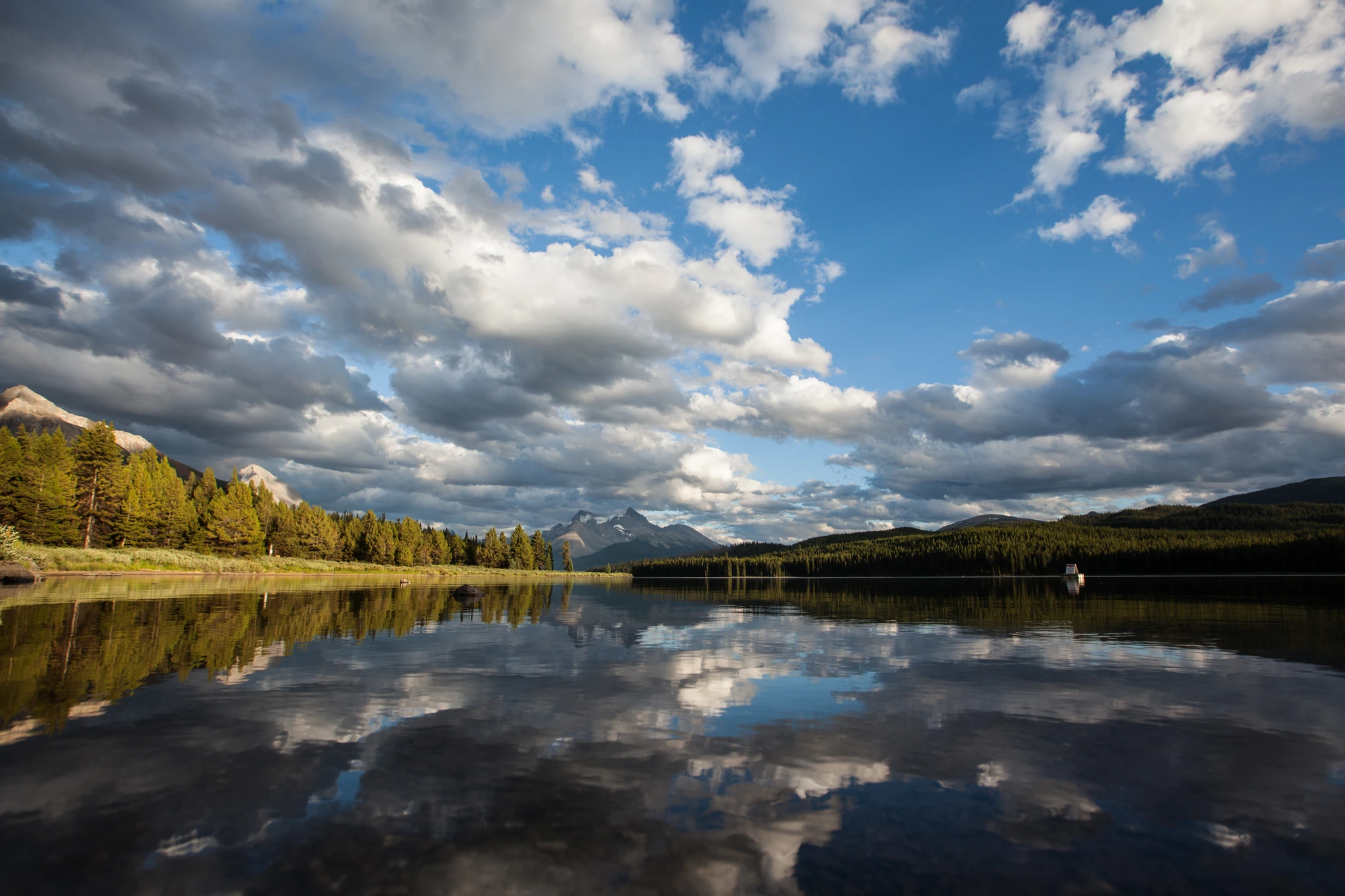 Cloud stacked over a mountain lake, the whole sky repeated in the water below